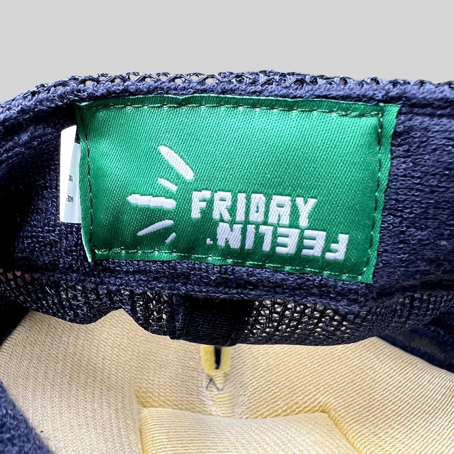 Raree Finds Friday Feelin’ green interior brand label inside a navy blue mesh trucker hat