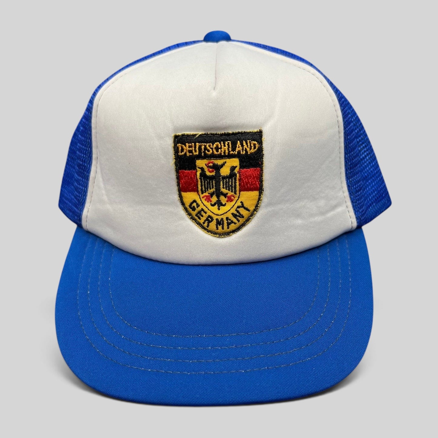 Raree Finds vintage Germany trucker hat with white foam front, royal blue mesh back, and German eagle crest patch.