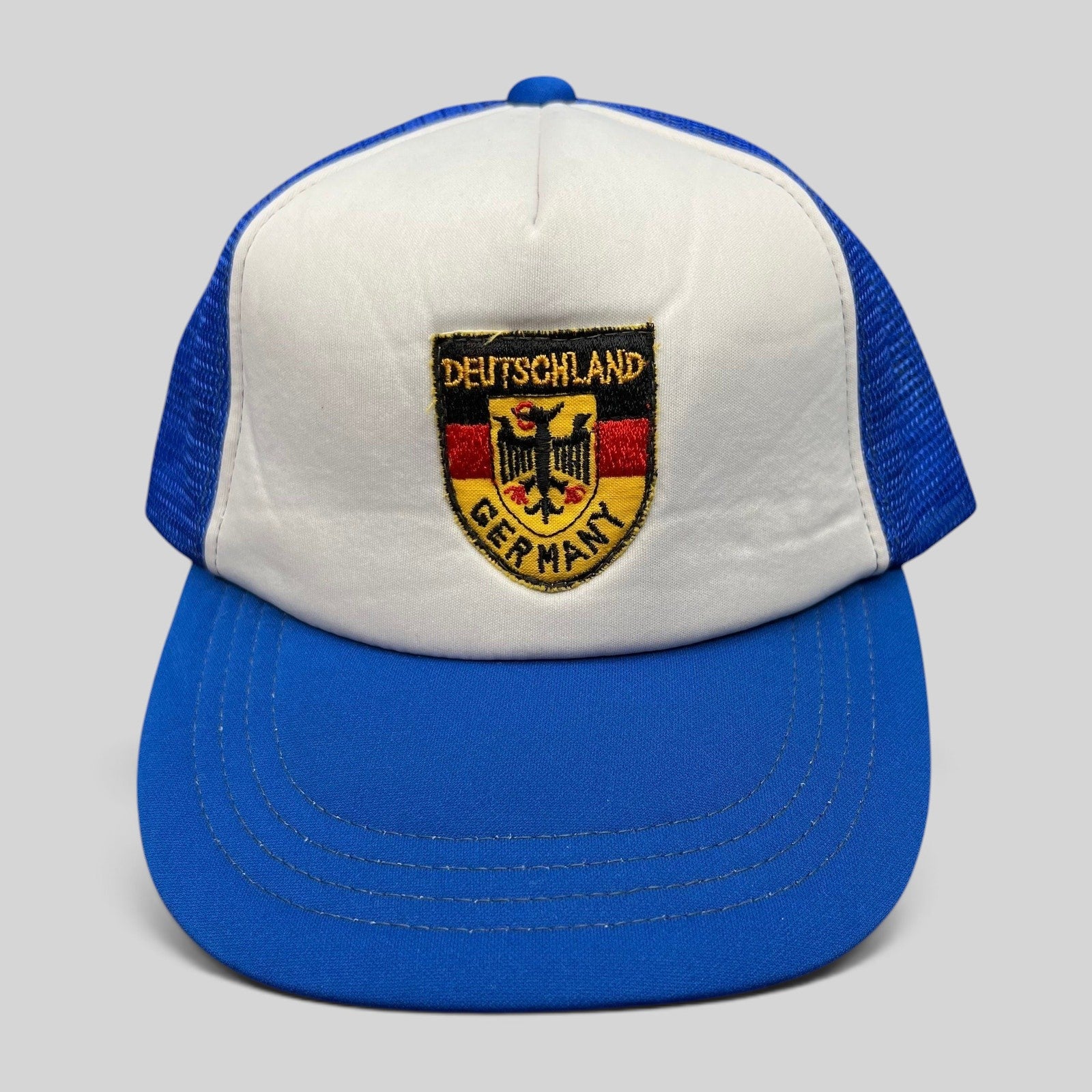 Raree Finds vintage Germany trucker hat with white foam front, royal blue mesh back, and German eagle crest patch.