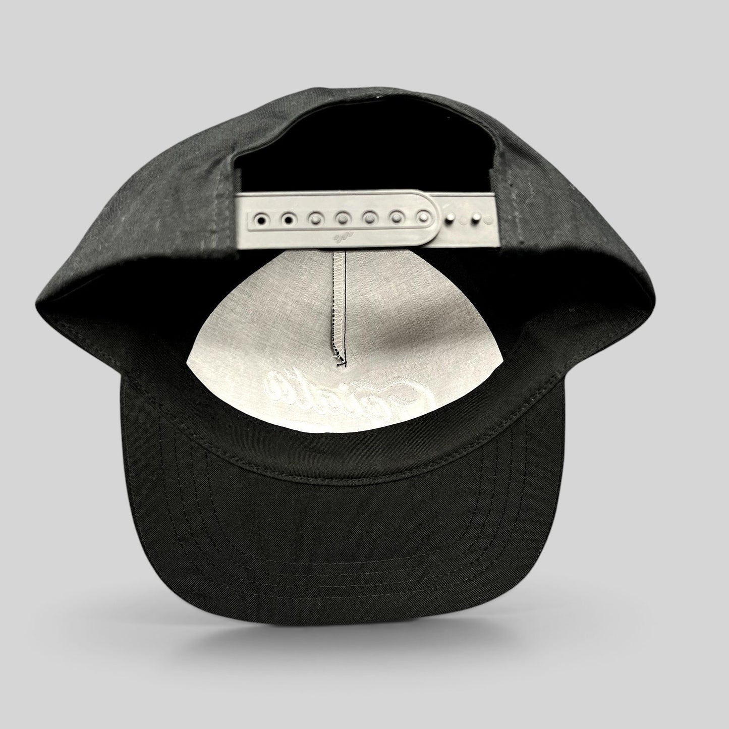 Raree Finds Ggiata LA black snapback hat showing the adjustable plastic snap closure and interior crown detail