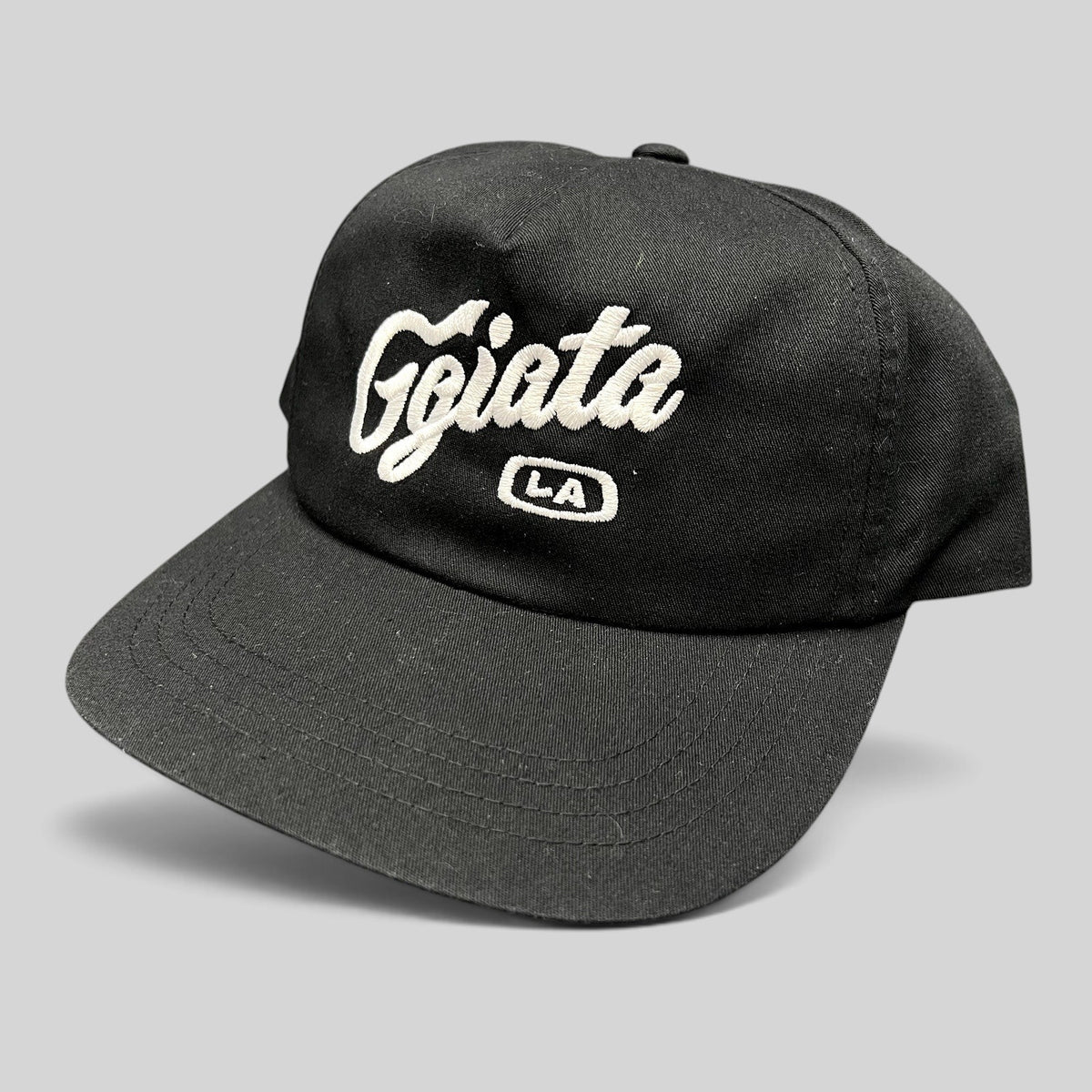 Raree Finds black Ggiata LA snapback hat with white embroidered script logo and flat brim on a structured crown