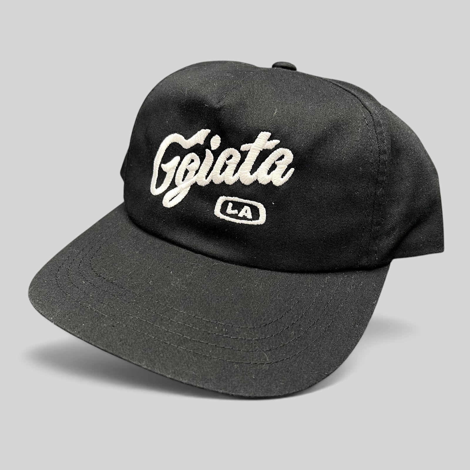 Raree Finds black Ggiata LA snapback hat with white embroidered script logo and flat brim on a structured crown