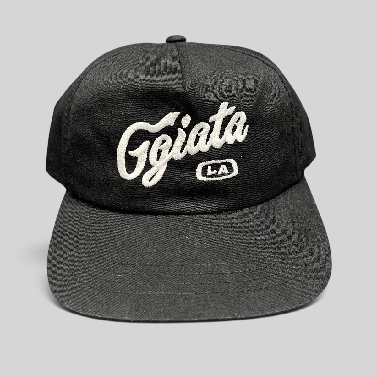 Raree Finds black Ggiata LA snapback hat with white cursive script embroidery and flat brim on a structured crown.