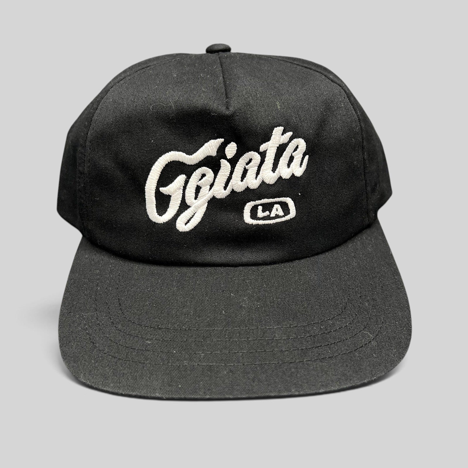 Raree Finds black Ggiata LA snapback hat with white cursive script embroidery and flat brim on a structured crown.