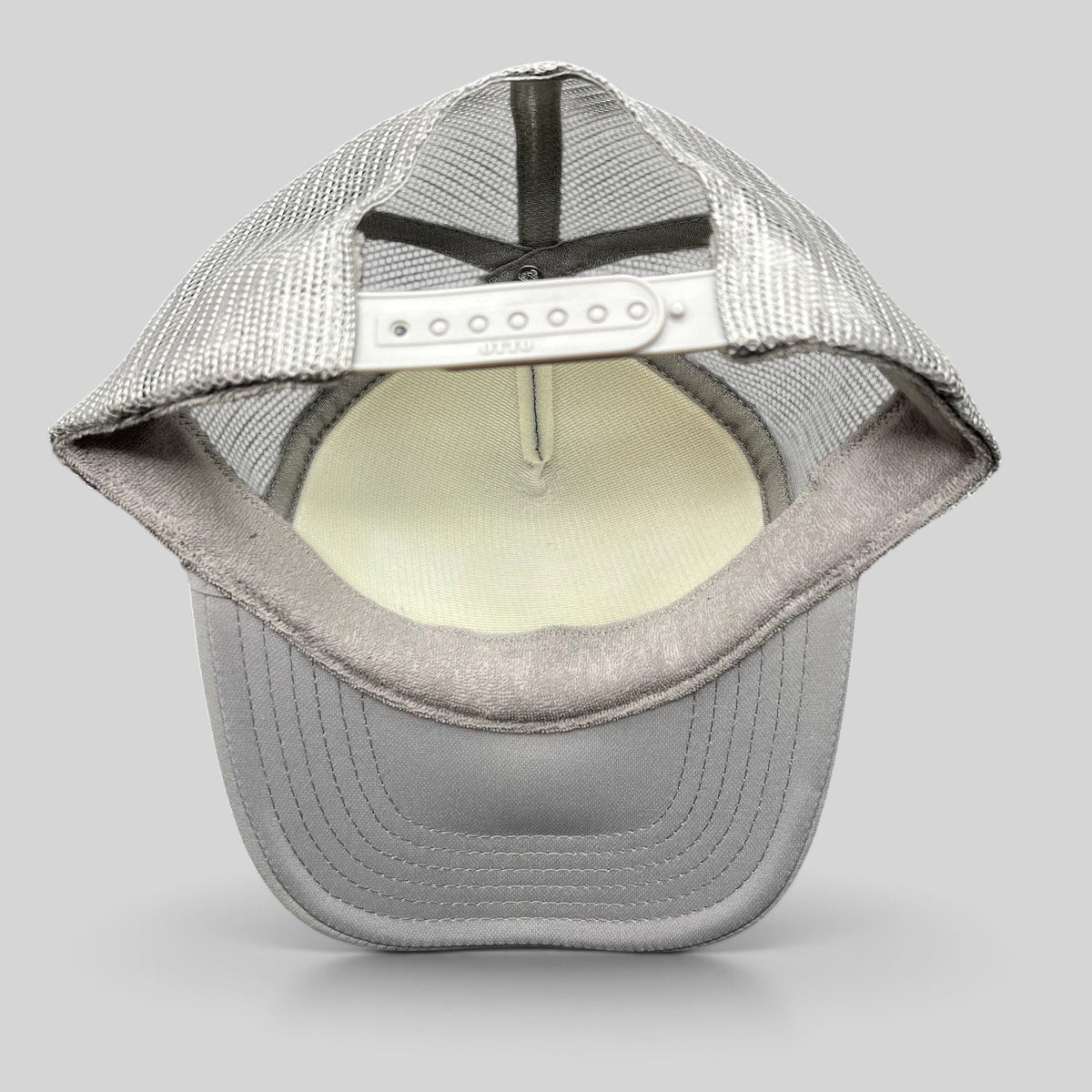 Raree Finds gray OTTO trucker hat interior view showing mesh backing, foam crown, and adjustable snapback closure