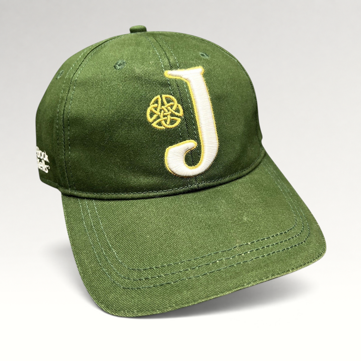 Raree Finds dark green strapback hat with an embroidered white J logo and gold Celtic knot, inspired by Book of Kells.