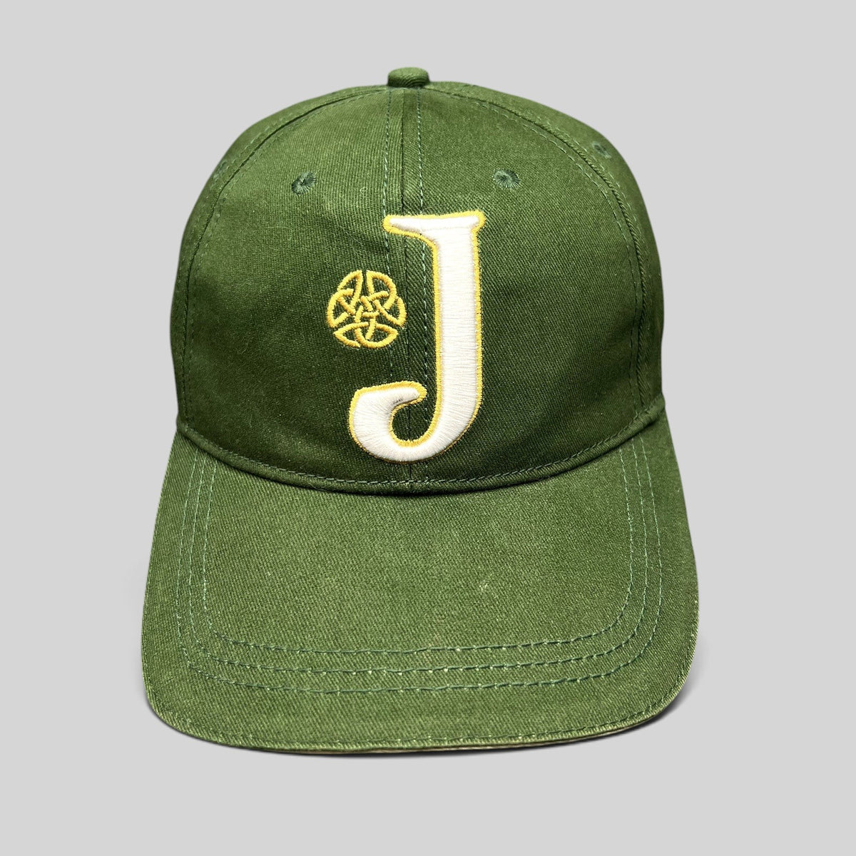 Raree Finds dark green strapback hat with an embroidered white J logo and gold Celtic knot symbol on the front.