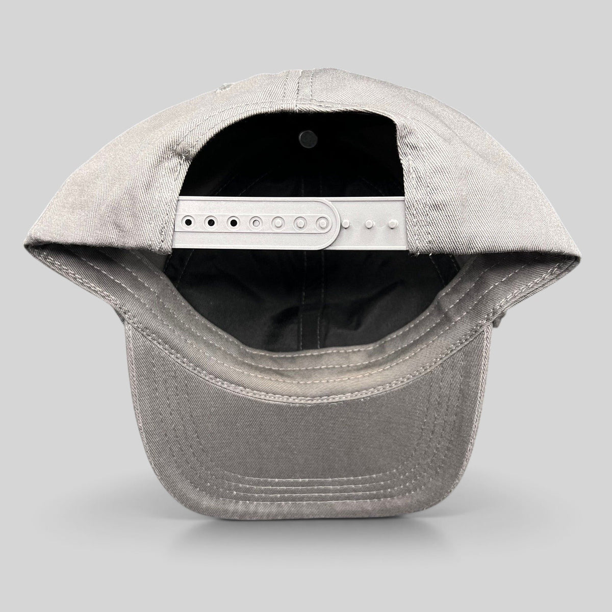 Raree Finds grey cotton twill snapback hat showing the adjustable plastic closure and interior construction