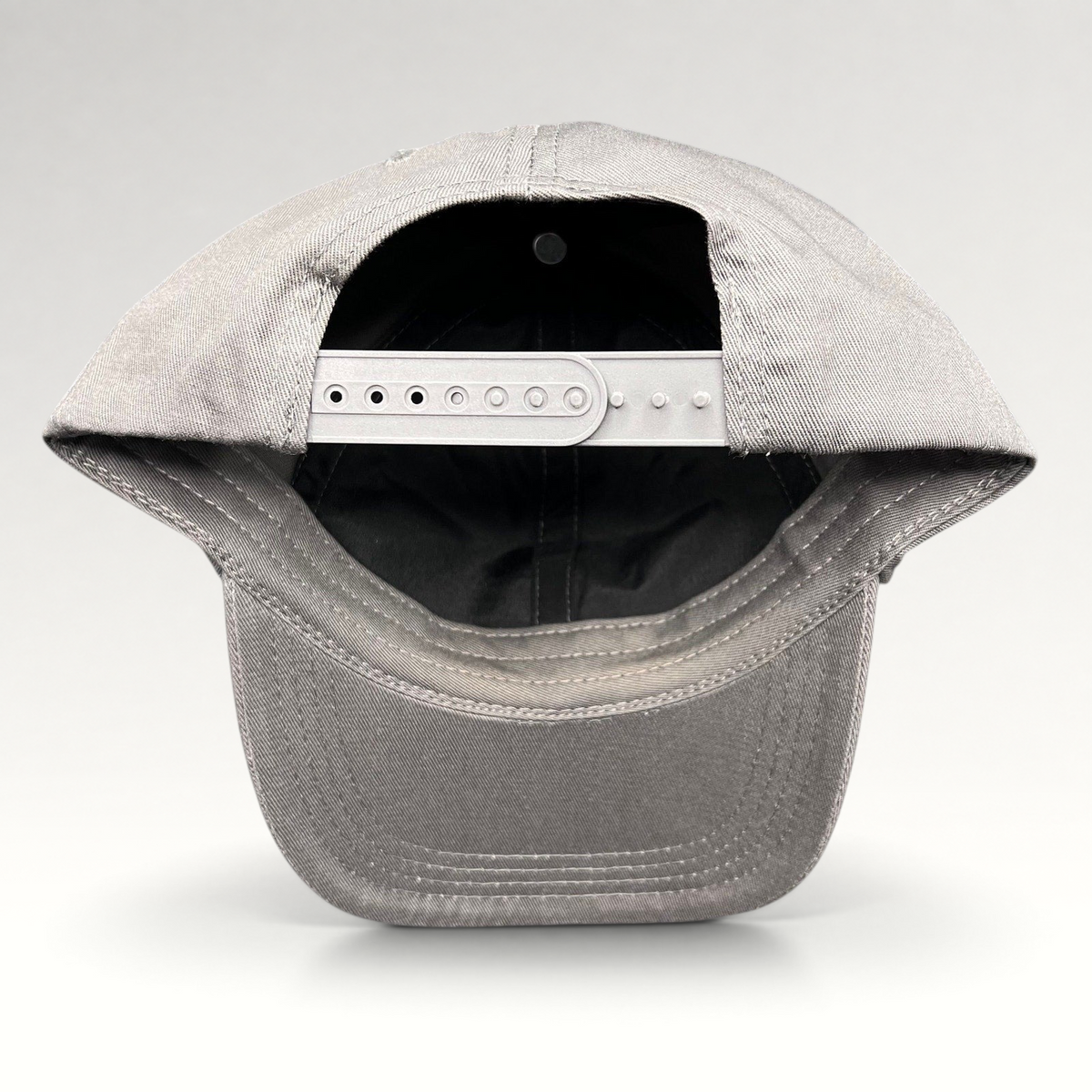 Raree Finds grey cotton twill snapback hat showing the adjustable plastic closure and interior construction