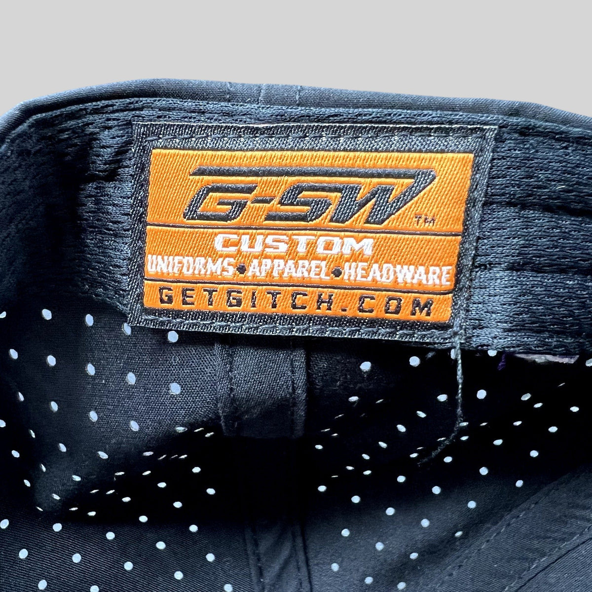 Raree Finds GSW Custom Apparel interior label inside a black perforated snapback hat from The Late Game production