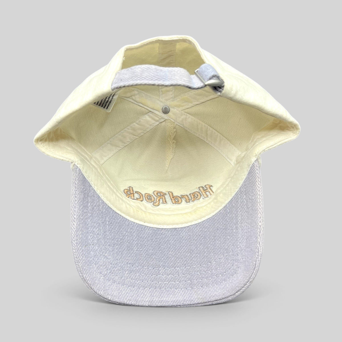Raree Finds Hard Rock Cafe strapback hat with cream crown, lavender brim, and adjustable metal slider buckle.