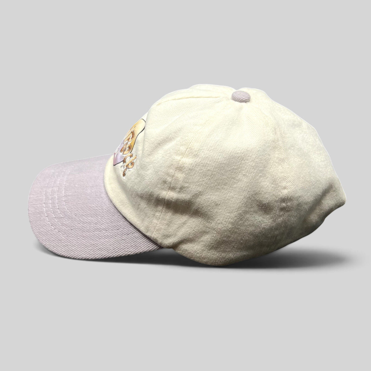 Raree Finds Hard Rock Cafe pastel dad hat with a cream cotton crown and lavender brim, side profile view.