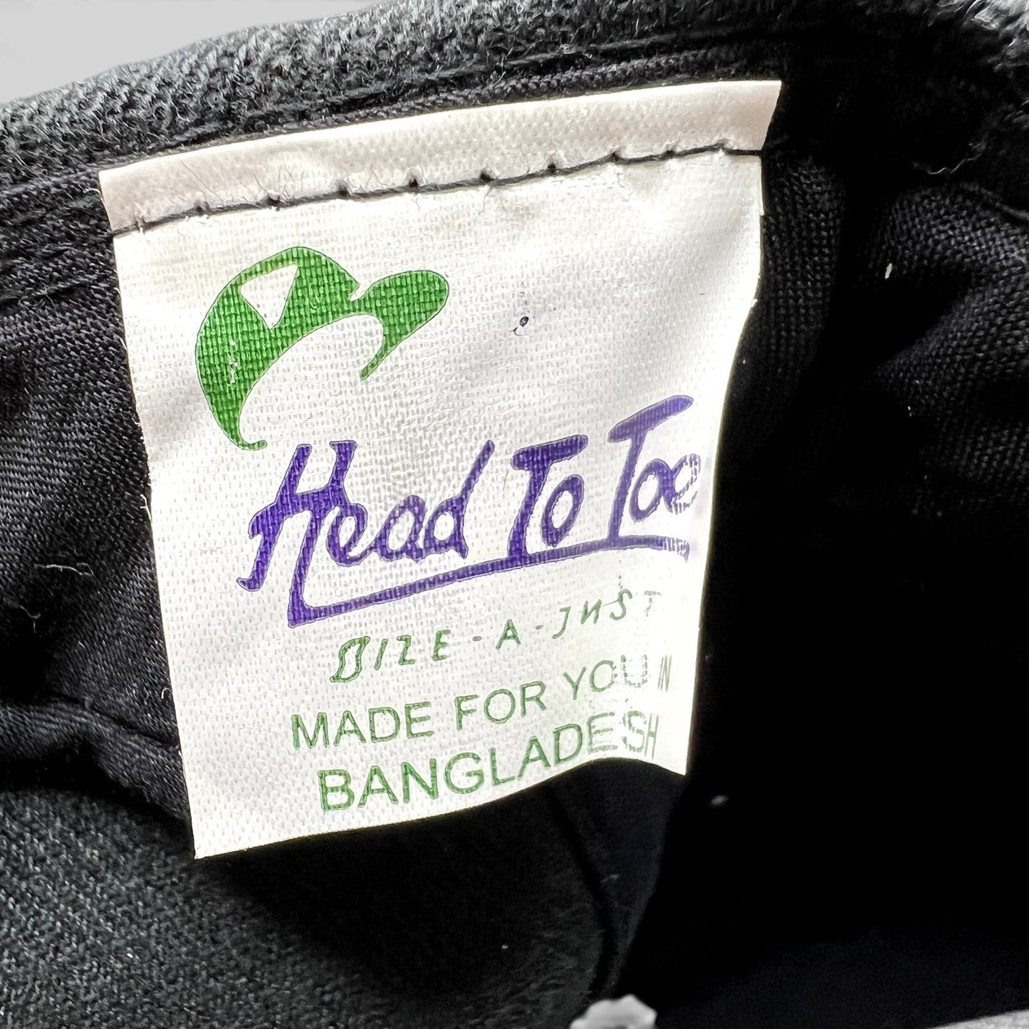 Raree Finds Head To Toe brand interior tag on a black Acura snapback hat, showing manufacturing details.