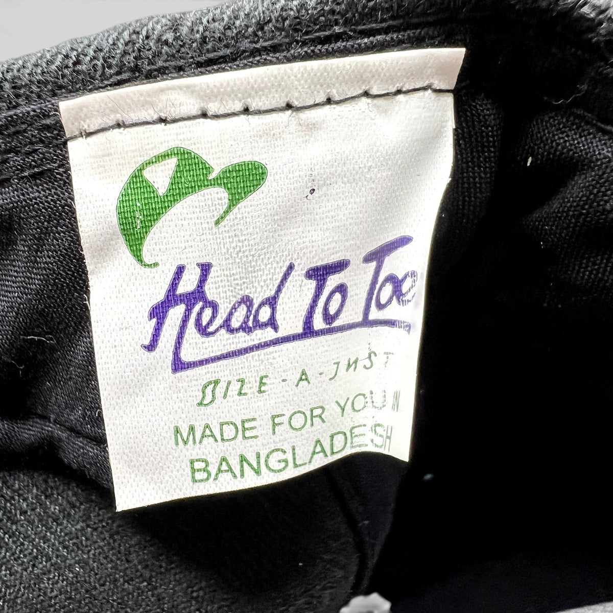 Raree Finds Head To Toe brand interior tag on a black Acura snapback hat, showing manufacturing details.