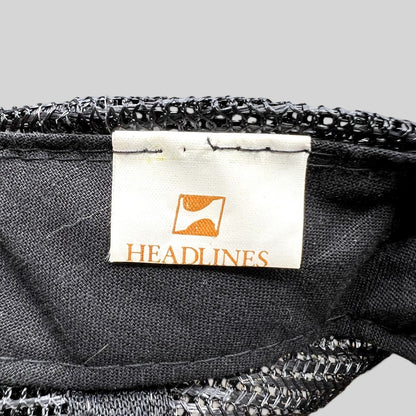 Raree Finds vintage Headlines brand tag inside a black mesh trucker hat with white fabric and orange logo detail
