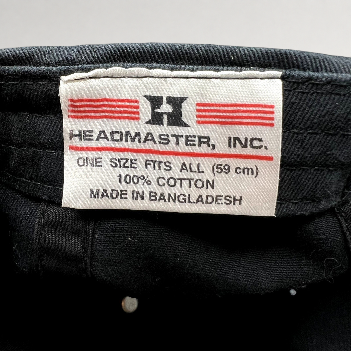 Raree Finds black cotton strapback hat interior tag showing Headmaster Inc branding and 100 percent cotton material