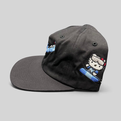 Raree Finds black cotton snapback hat featuring Hello Kitty skiing embroidery and blue script logo on the side panel.