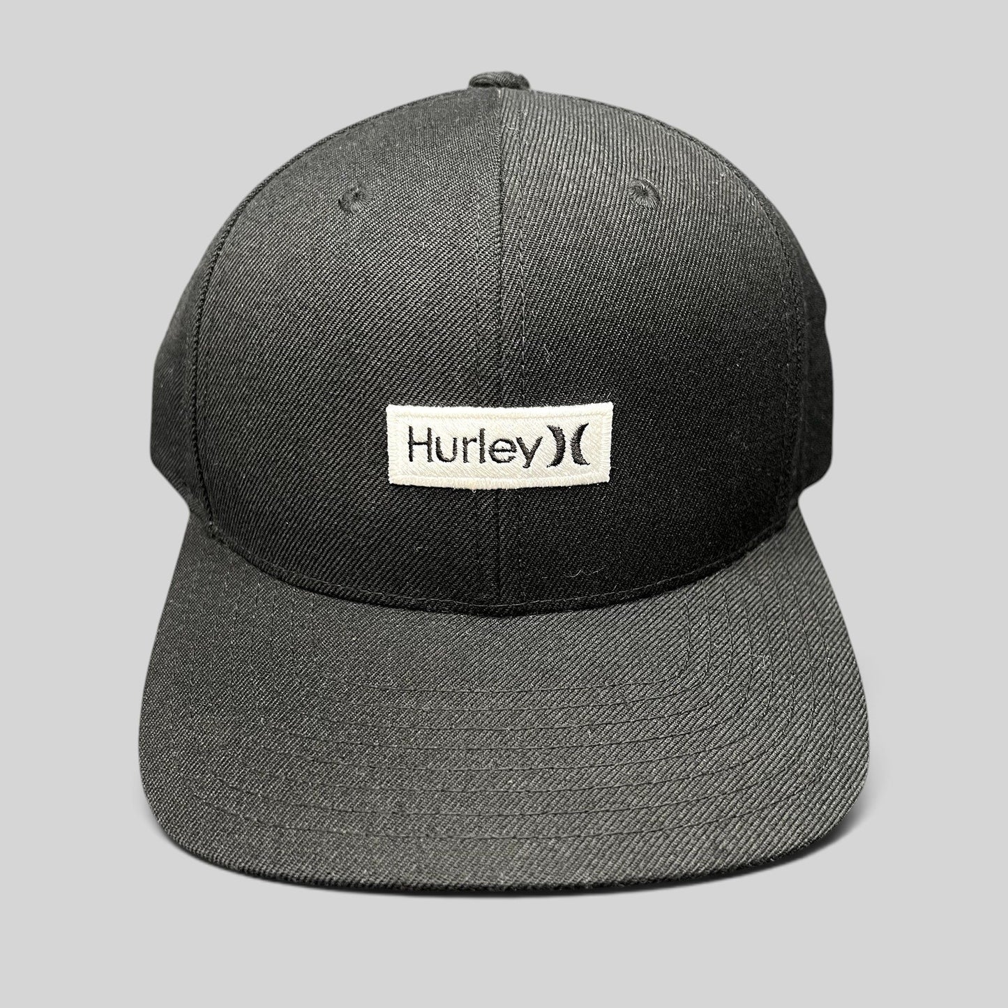Raree Finds black Hurley snapback hat with a white woven logo patch on a structured Yupoong crown and flat brim.