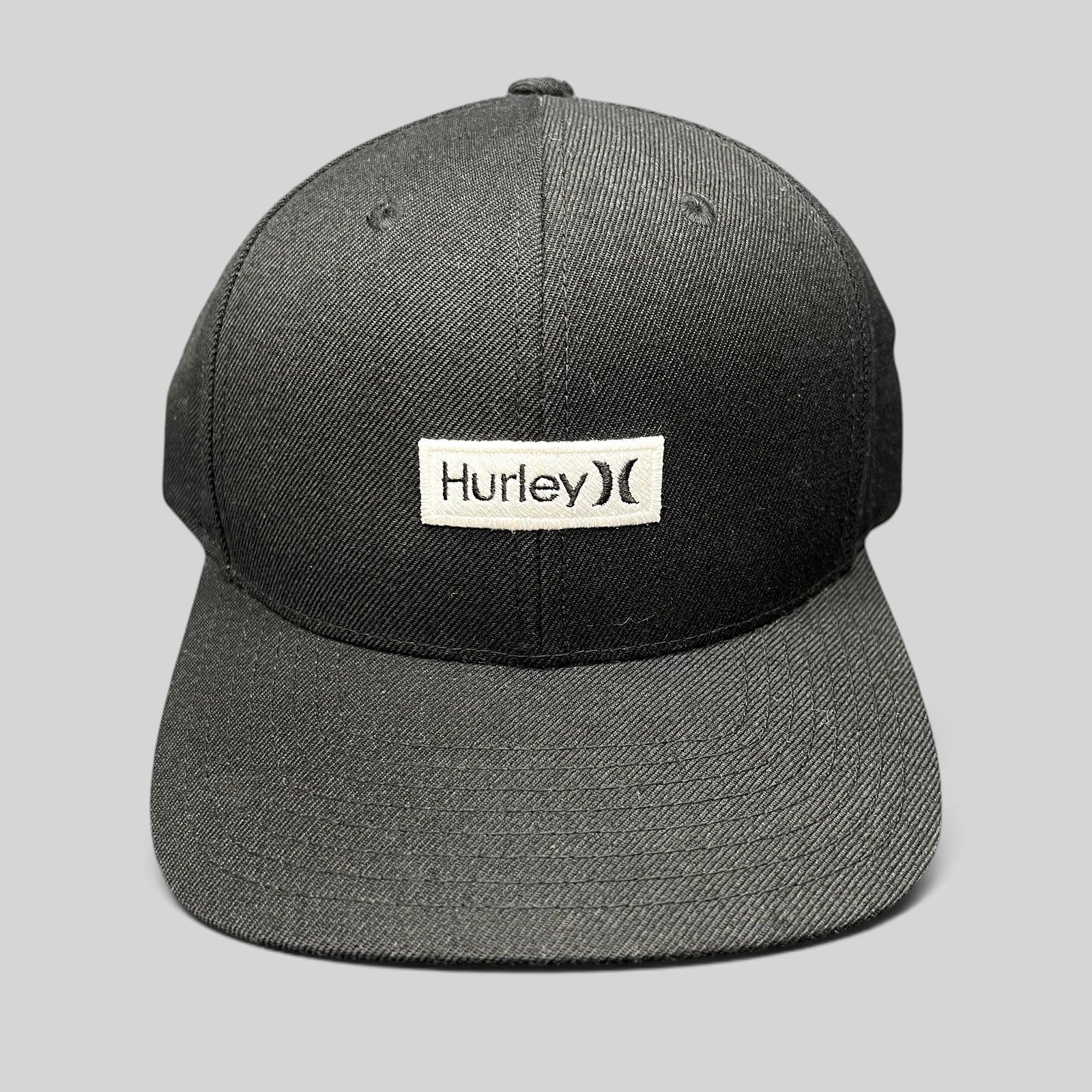 Raree Finds black Hurley snapback hat with a white woven logo patch on a structured Yupoong crown and flat brim.