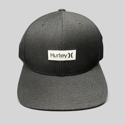 Raree Finds black Hurley snapback hat with a white woven logo patch on a structured Yupoong crown and flat brim.