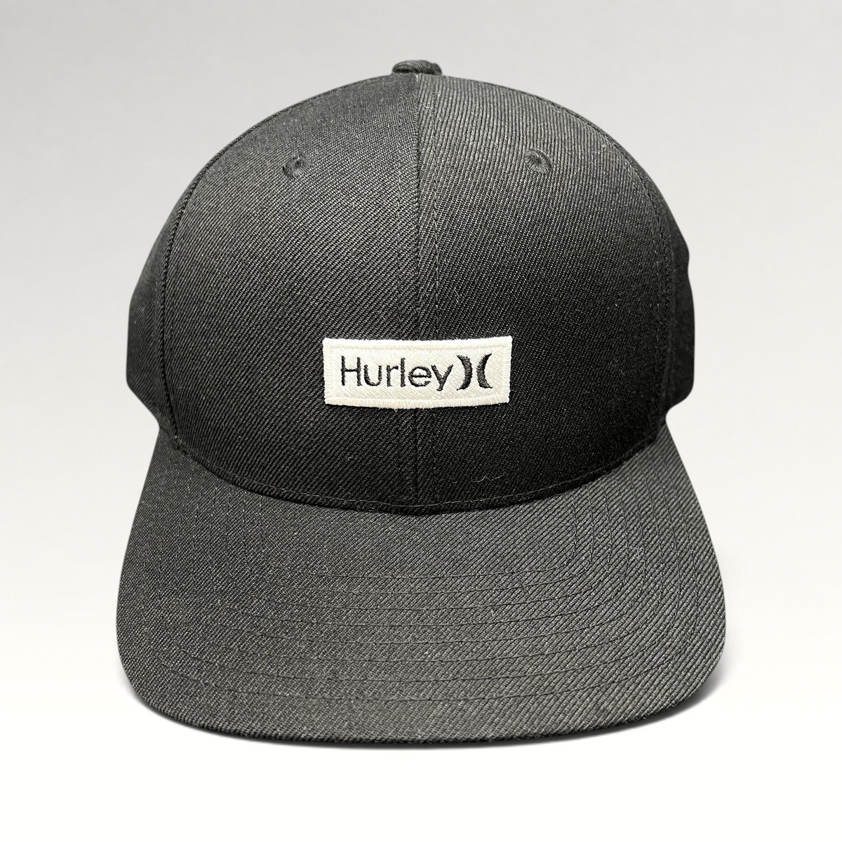 Raree Finds black Hurley snapback hat with a white woven logo patch on a structured Yupoong crown and flat brim.