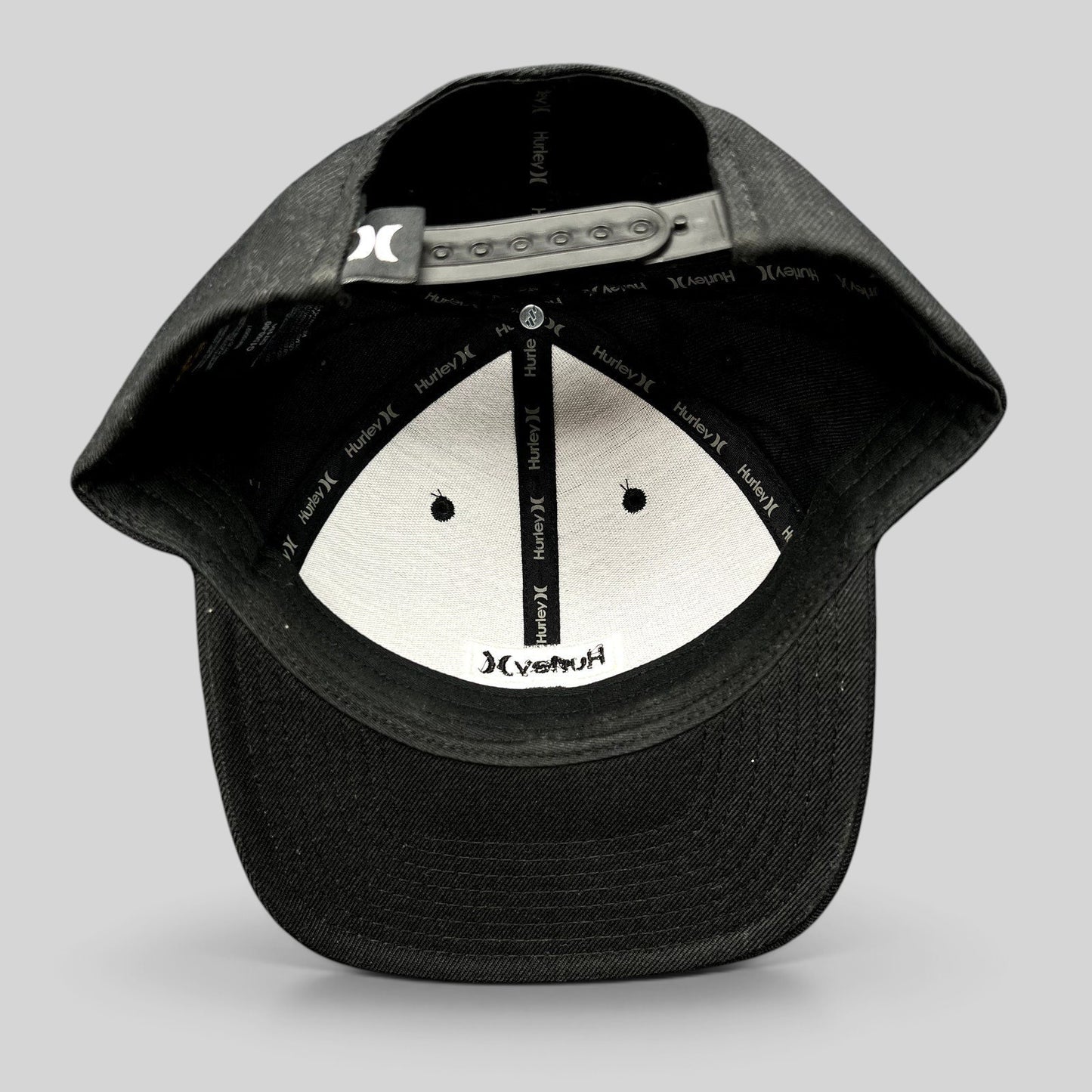 Raree Finds black Hurley Yupoong snapback hat interior view showing branded taping and adjustable plastic closure