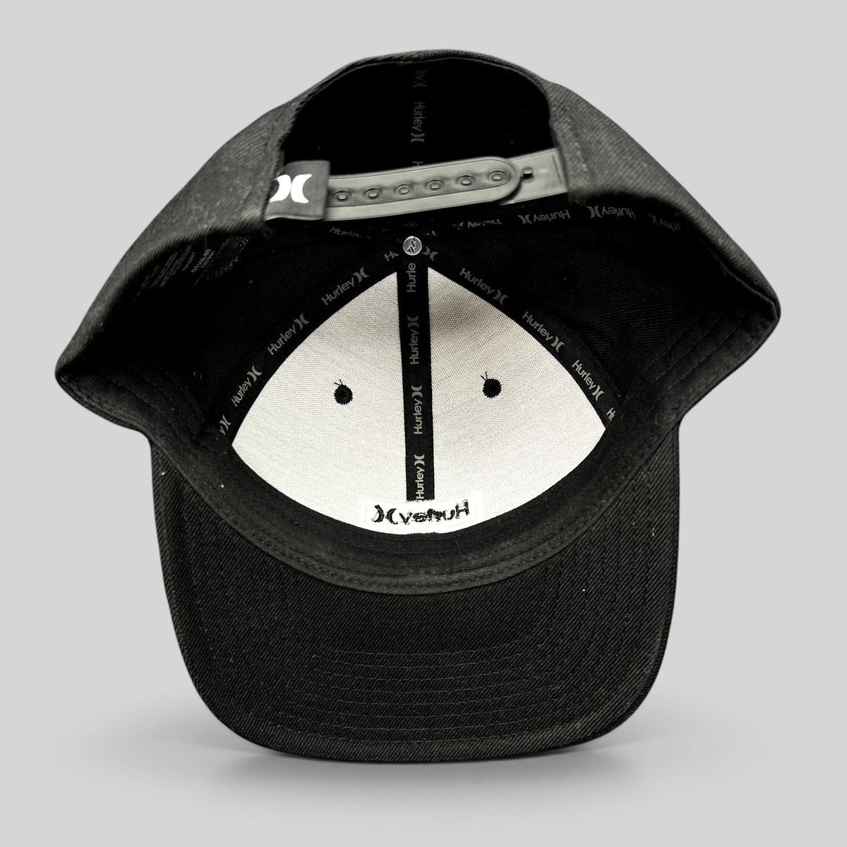 Raree Finds black Hurley Yupoong snapback hat interior view showing branded taping and adjustable plastic closure