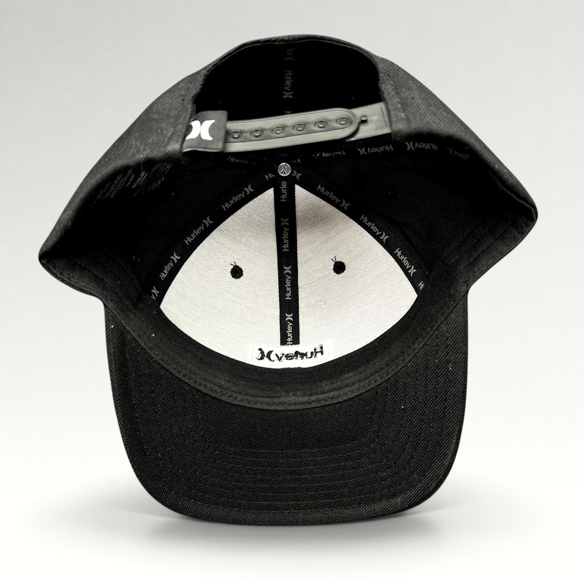 Raree Finds black Hurley Yupoong snapback hat interior view showing branded taping and adjustable plastic closure