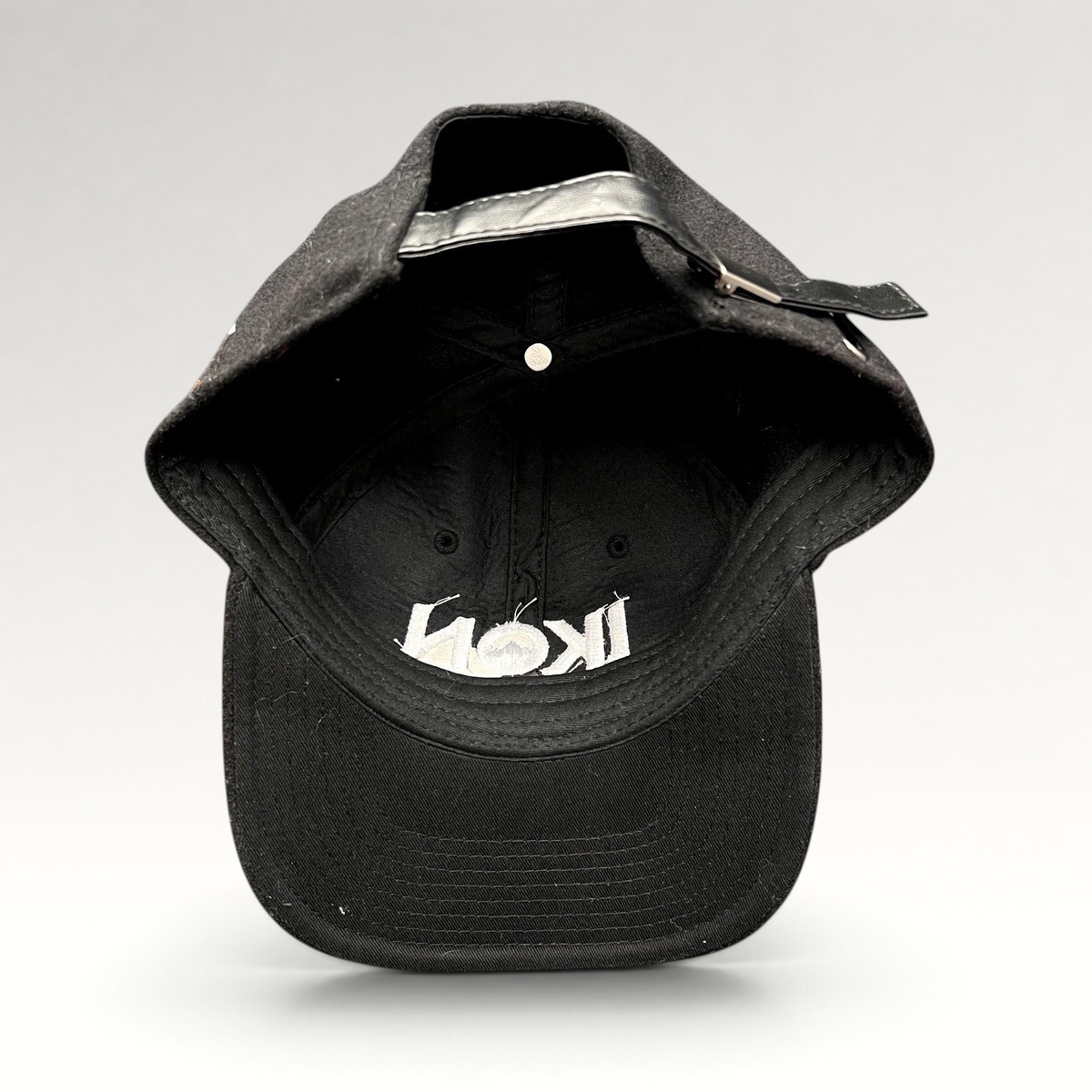Raree Finds black wool-blend Ikon Pass strapback hat with white embroidered logo and adjustable leather-style strap.
