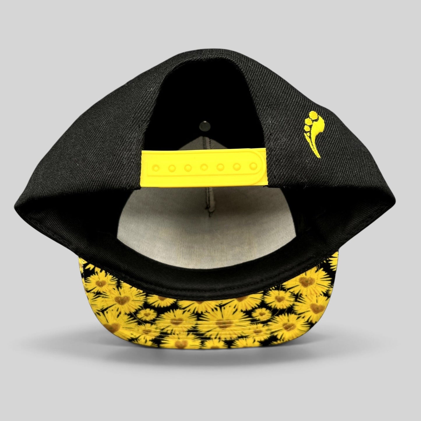 Raree Finds Insomniac EDC snapback hat featuring a black crown, yellow snap closure, and sunflower-print flat brim.