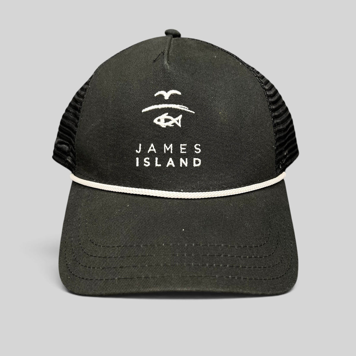 Raree Finds black trucker hat with white James Island coastal logo embroidery, mesh back, and rope detail on brim.