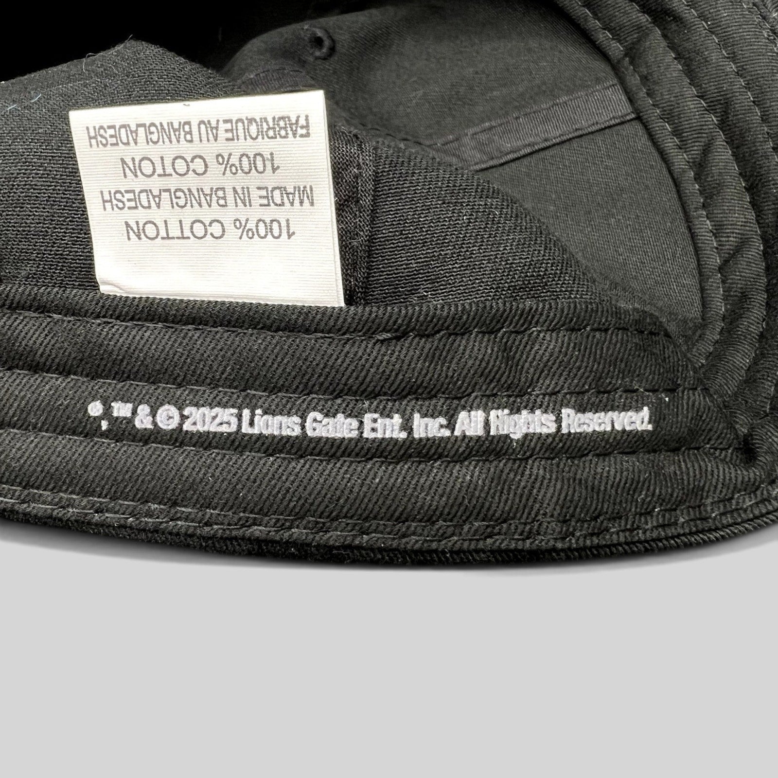 Raree Finds black cotton strapback hat interior showing 2025 Lionsgate copyright label and 100% cotton tag