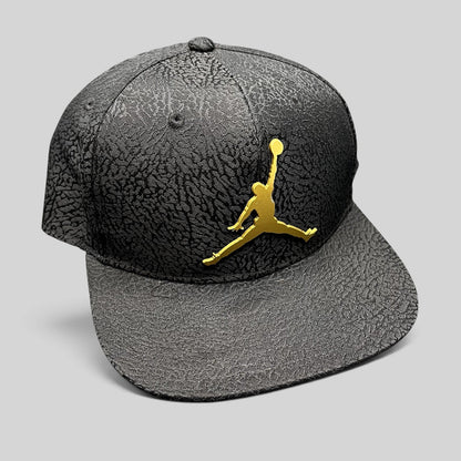 Raree Finds youth Jordan snapback hat in black with elephant print texture and a metallic gold Jumpman logo.