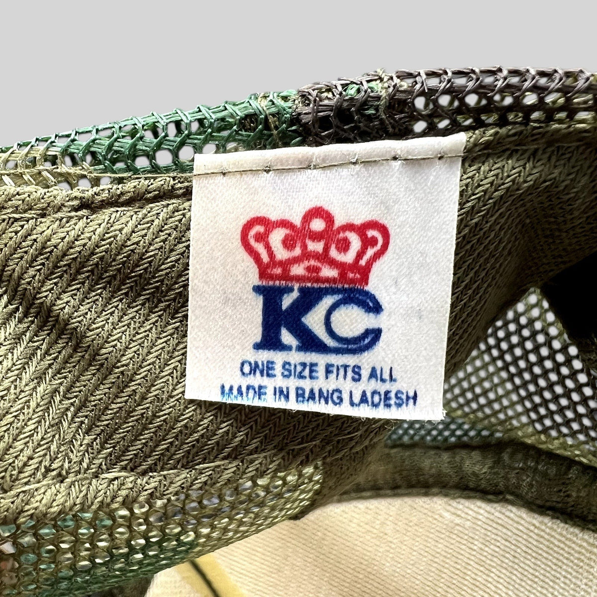 Raree Finds KC Cap brand label inside a vintage olive green and woodland camouflage mesh trucker hat