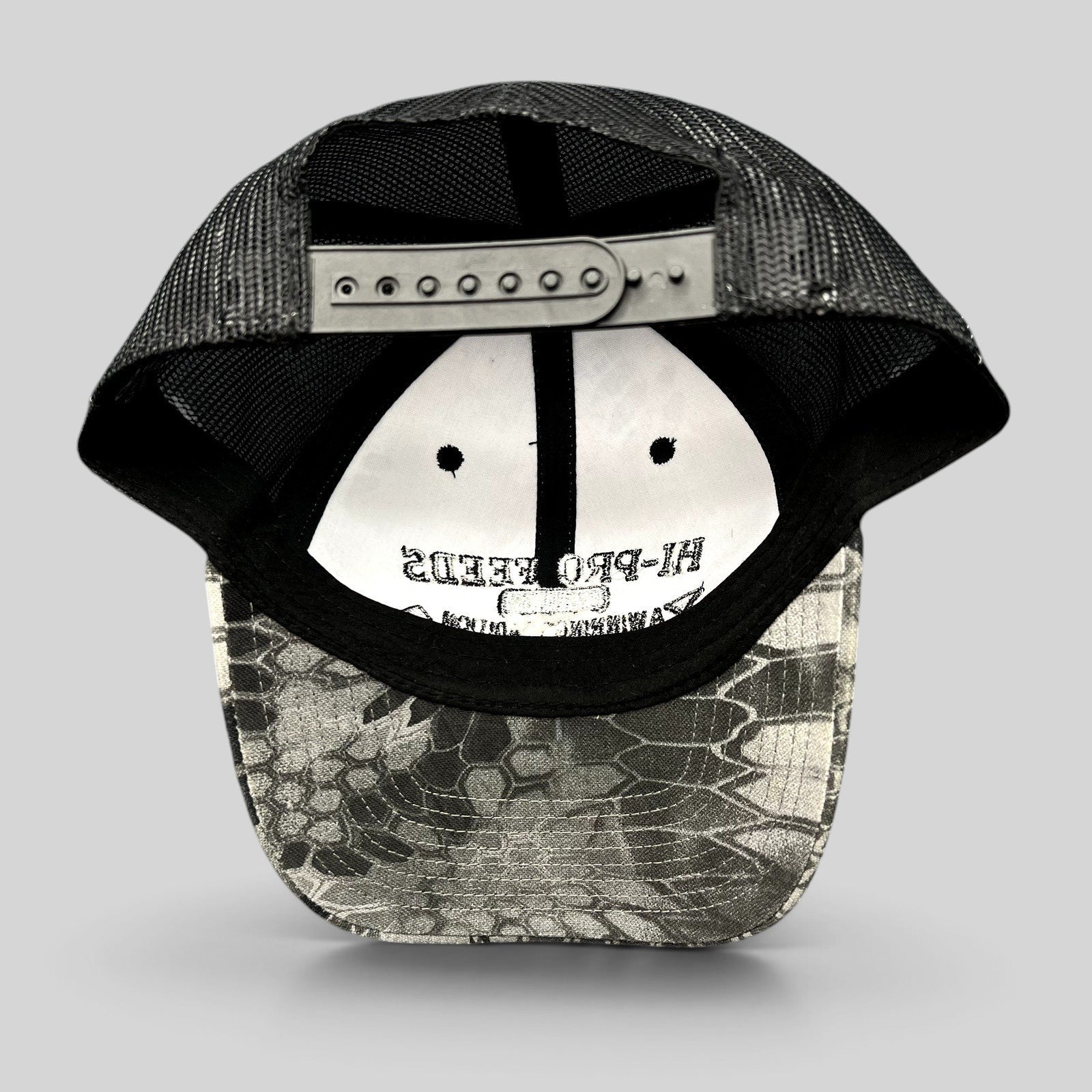 Raree Finds Hi-Pro Feeds trucker hat with black mesh back and Kryptek Raid camo bill, showing adjustable snapback.