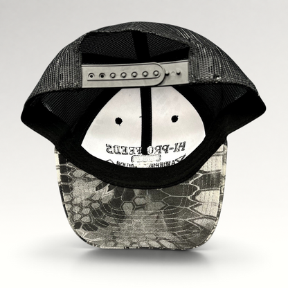 Raree Finds Hi-Pro Feeds trucker hat with black mesh back and Kryptek Raid camo bill, showing adjustable snapback.