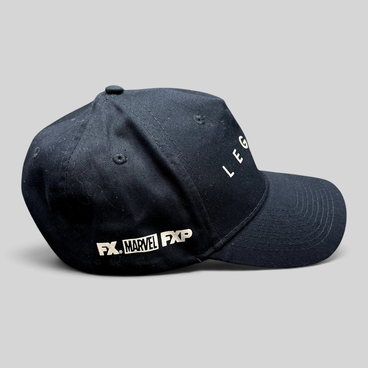 Raree Finds black Legion Marvel FX TV series strapback hat with white logo embroidery on a side profile view.
