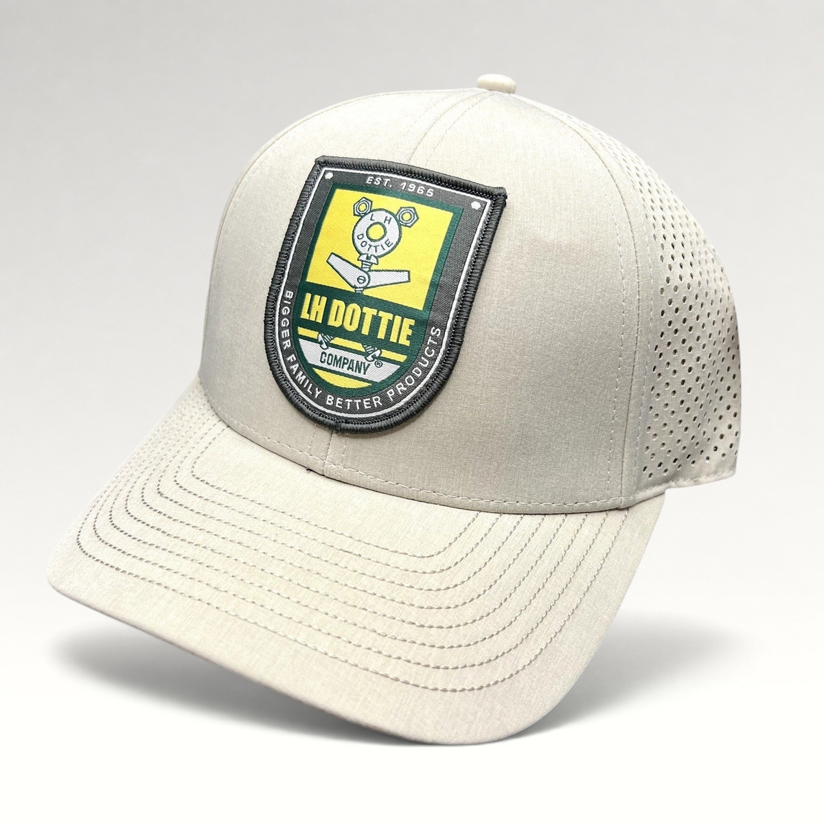 Raree Finds LH Dottie Company tan snapback hat with embroidered shield logo, perforated panels, and curved brim.