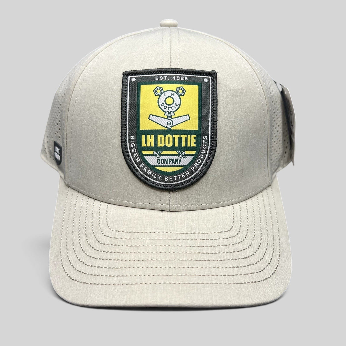 Raree Finds LH Dottie Company tan snapback hat with embroidered shield patch, perforated panels, and curved brim.