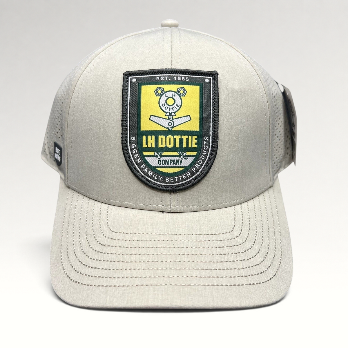 Raree Finds LH Dottie Company tan snapback hat with embroidered shield patch, perforated panels, and curved brim.