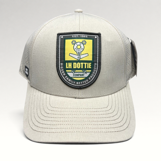 Raree Finds LH Dottie Company tan snapback hat with embroidered shield patch, perforated panels, and curved brim.