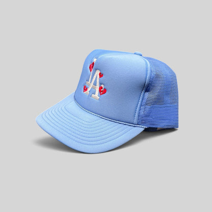Raree Finds light-blue trucker hat with white LA logo and red broken-heart embroidery on a foam front and mesh back.