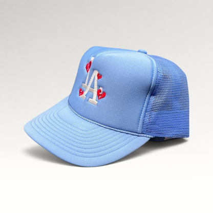 Raree Finds light-blue trucker hat with white LA logo and red broken-heart embroidery on a foam front and mesh back.