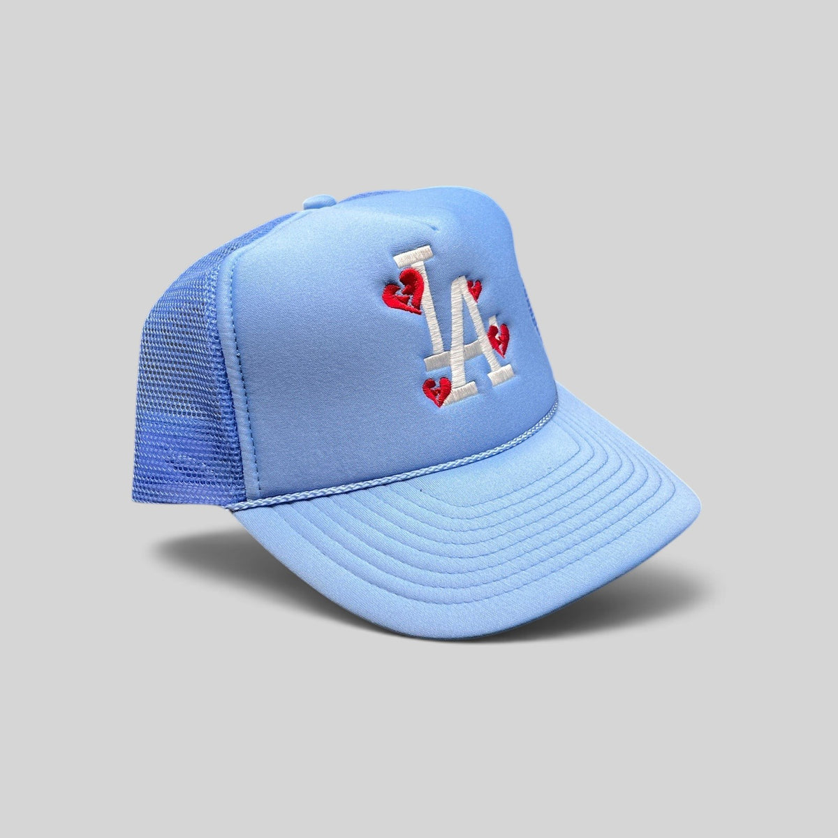 Raree Finds light-blue Y2K trucker hat with white LA logo and red broken-heart embroidery on a foam-front mesh cap.