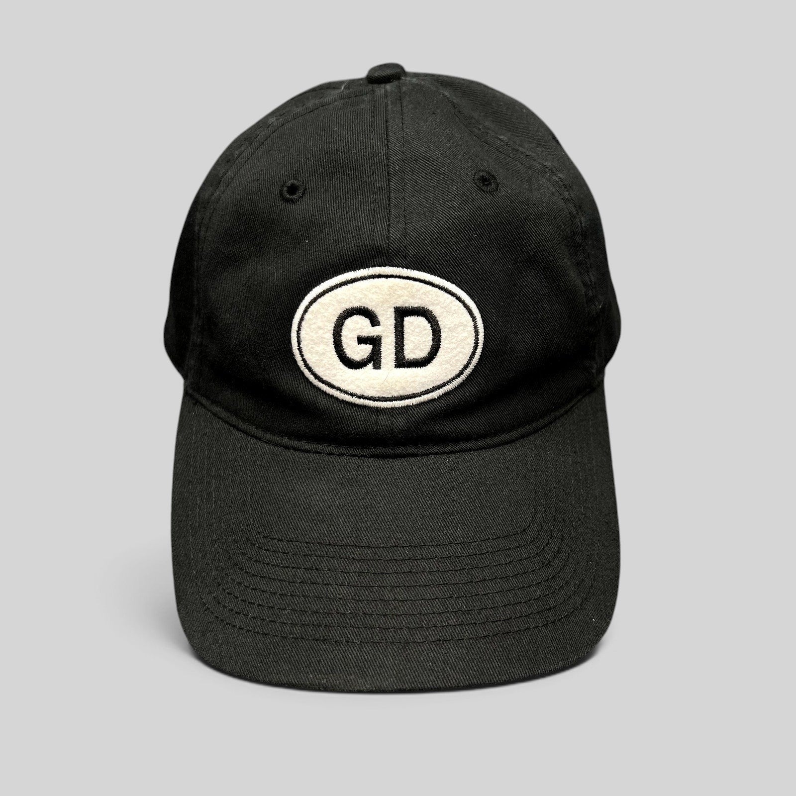 Raree Finds black cotton strapback hat by Liquid Blue featuring a white oval GD logo patch on the front