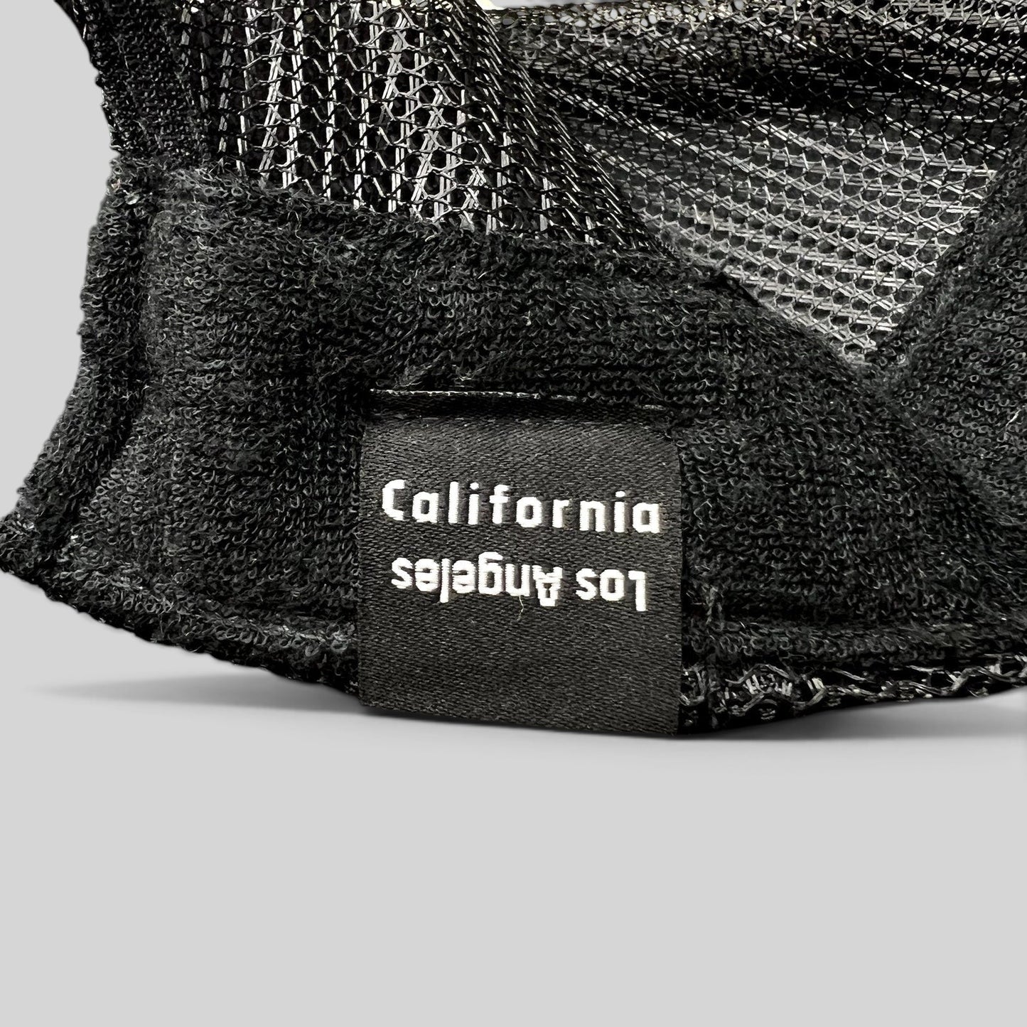 Raree Finds black trucker hat interior tag featuring Los Angeles California text on a mesh back cap