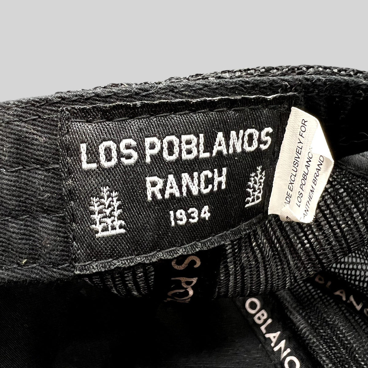 Raree Finds Los Poblanos Ranch 1934 black trucker hat interior label with branding and mesh panel detail