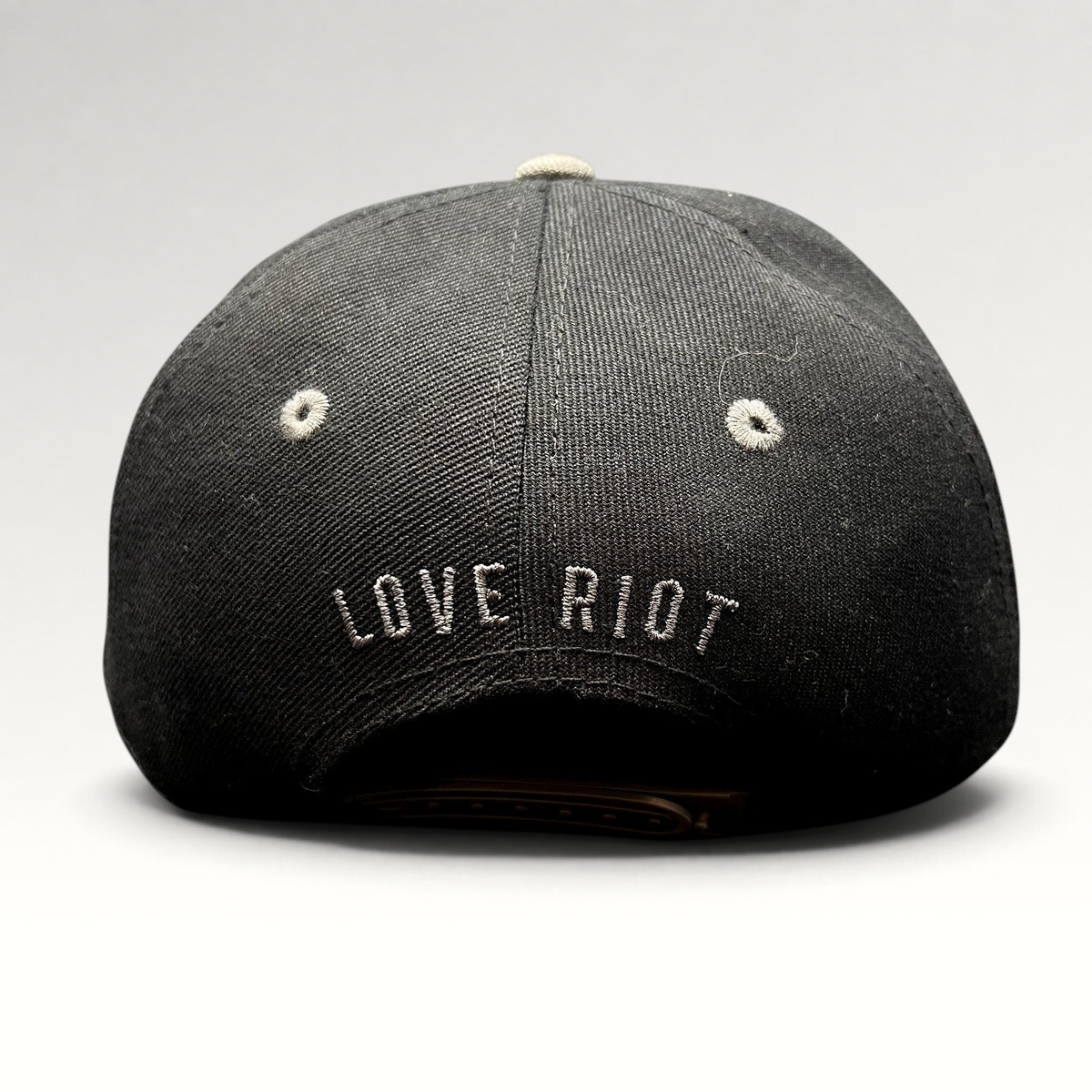 Raree Finds black snapback hat with Love Riot embroidered on the back and gray eyelet detailing