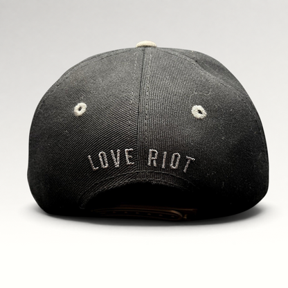 Raree Finds black snapback hat with Love Riot embroidered on the back and gray eyelet detailing