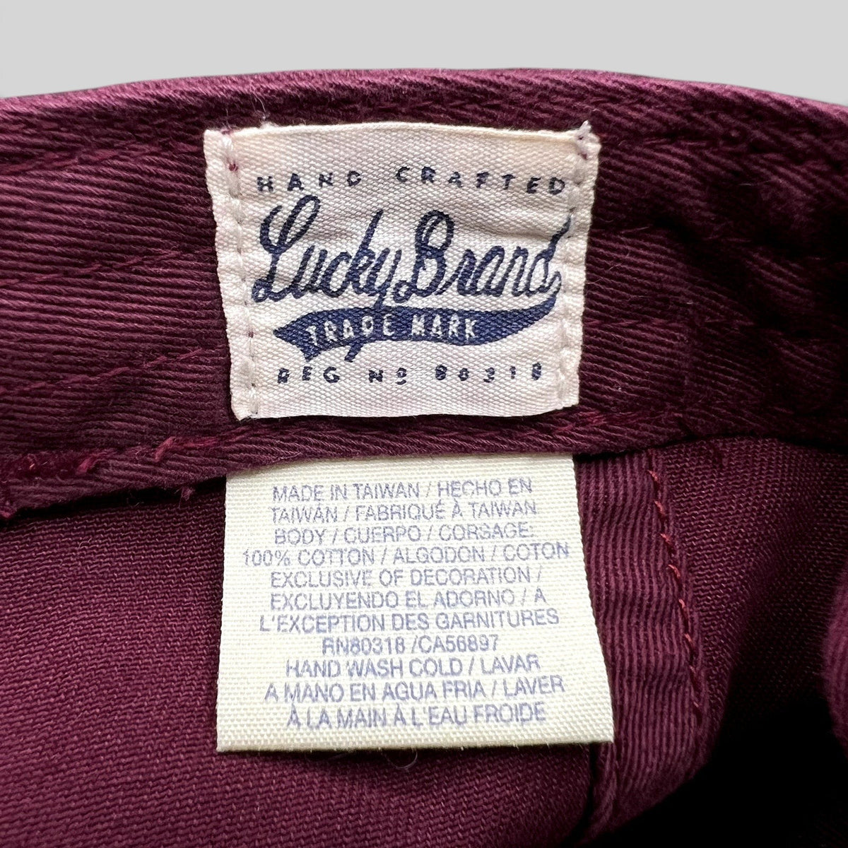 Raree Finds Lucky Brand x Budweiser hat interior label showing cotton material and care instructions in burgundy